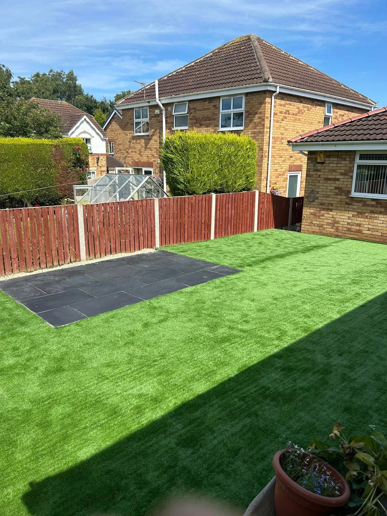 Artificial lawn and dark paved area in a completed garden