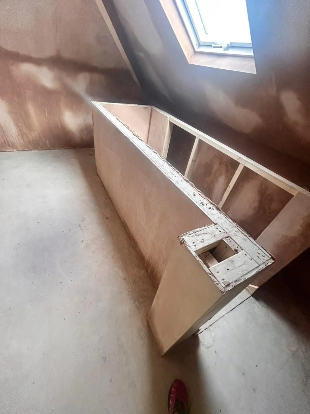 Plastered loft walls around a roof window and stair opening