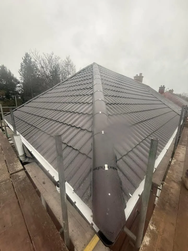 Completed grey tiled hip roof with ridge fittings and white fascia