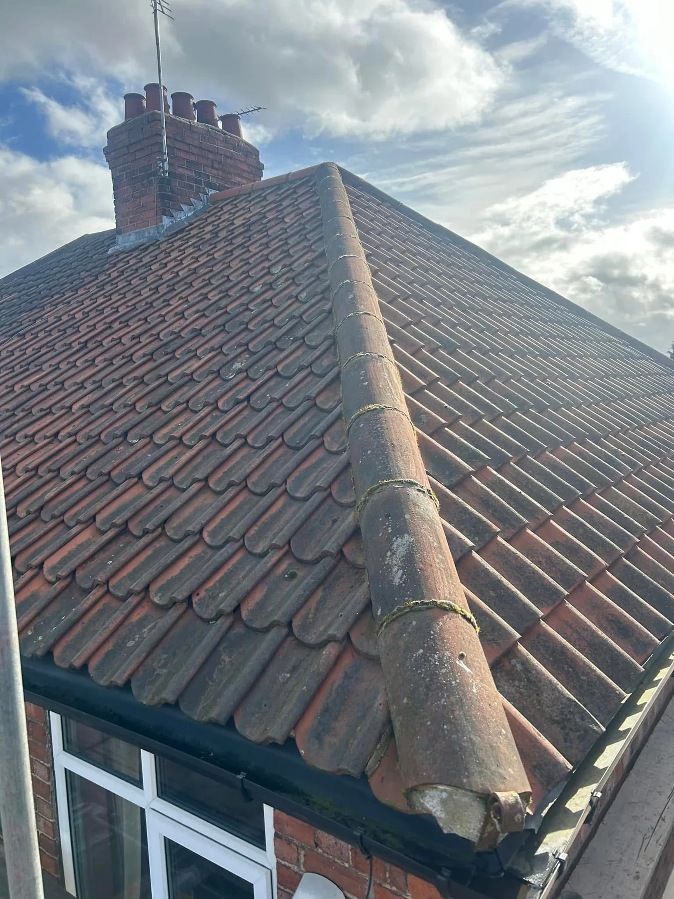 Existing weathered red roof tiles and hip ridge